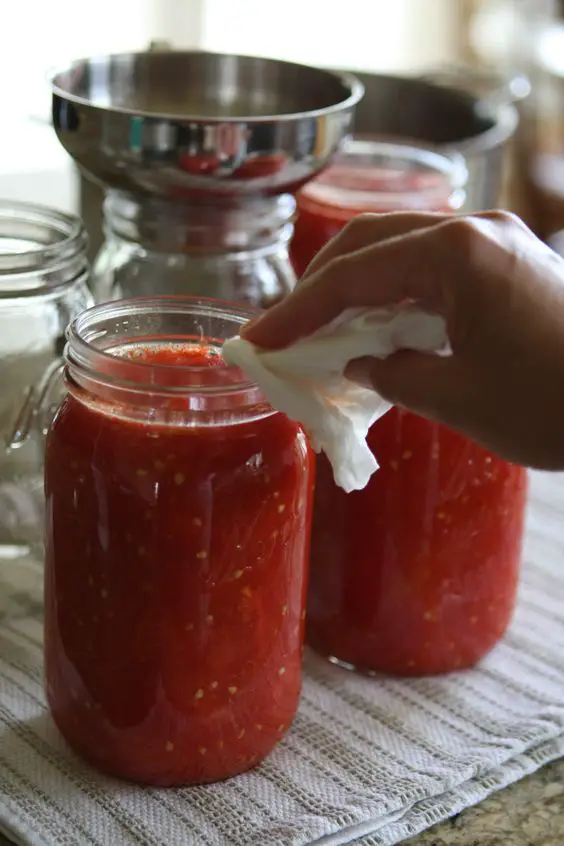 Wiping canning jars after canning tomatoes with Tomato Dirt
